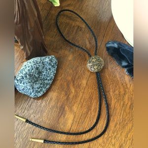 Brass with floral design bow low tie, on leather braided cord. Like new.